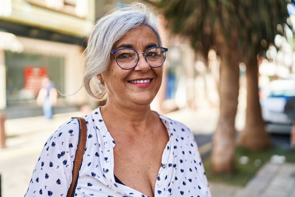 Mujer de mediana edad sonriendo confiada de pie en la calle - Foto, imagen
