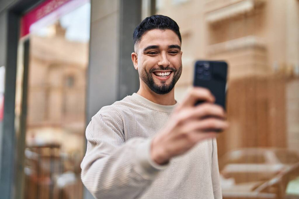 Young arab man smiling confident using smartphone at street - Foto, immagini