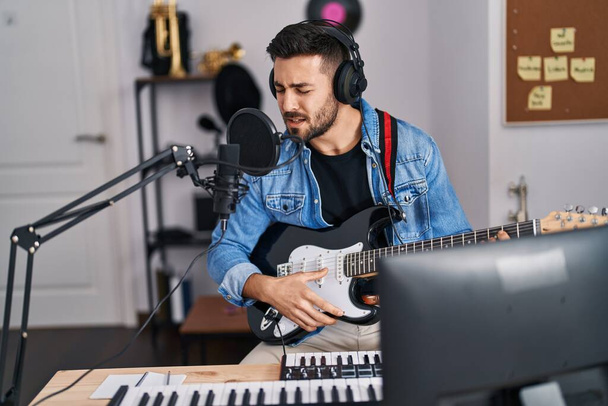Jeune homme hispanique chantant une chanson jouant de la guitare électrique au studio de musique - Photo, image