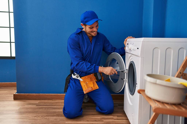 Joven técnico hispano reparando lavadora en la lavandería - Foto, Imagen