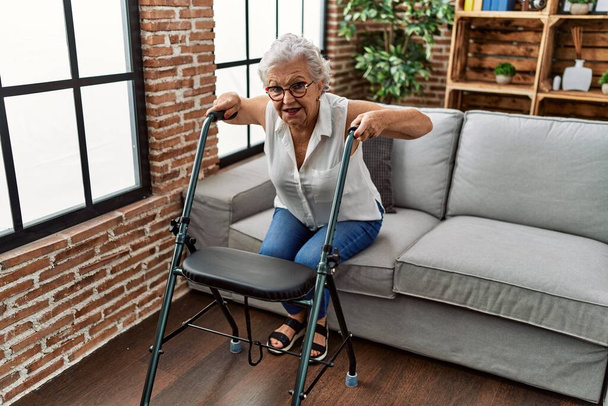 Patiente âgée aux cheveux gris soutenue pour une marchette en gériatrie - Photo, image
