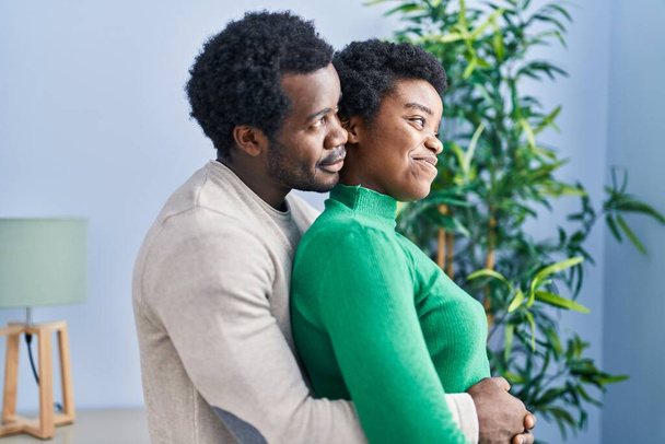 Afroamerikanisch Mann und Frau Paar umarmen einander stehend zu Hause - Foto, Bild