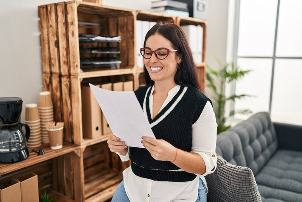 Young beautiful hispanic woman business worker reading document at office - Photo, Image