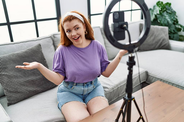 Young redhead woman having video call using smartphone at home - Photo, Image