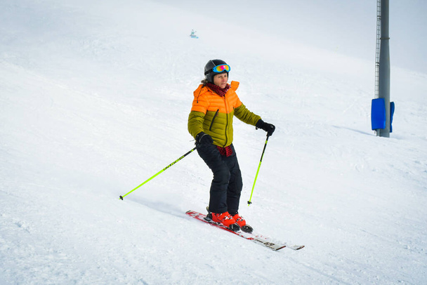 Гудаури, Грузия - 25 марта 2022 года: авантюристская кавказская женщина средних лет катается на лыжах, возбужденная снежными условиями в зимнем горнолыжном курорте на отдыхе - Фото, изображение