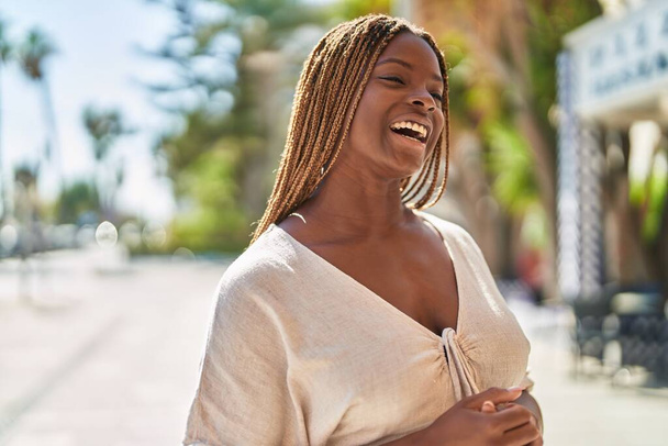 アフリカ系アメリカ人の女性が自信を持って公園の側を見て笑っている - 写真・画像