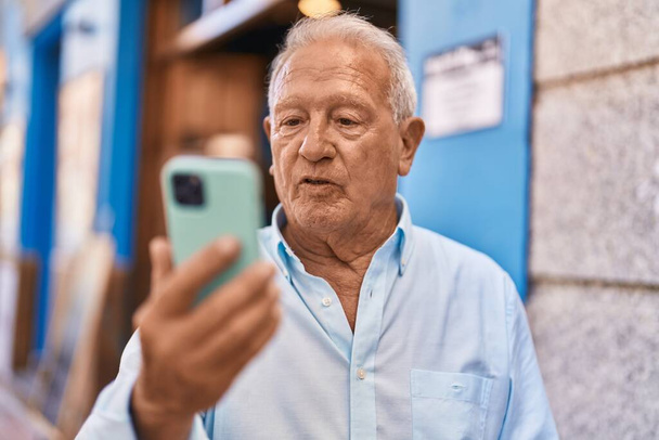 Senior grey-haired man using smartphone at street - Valokuva, kuva