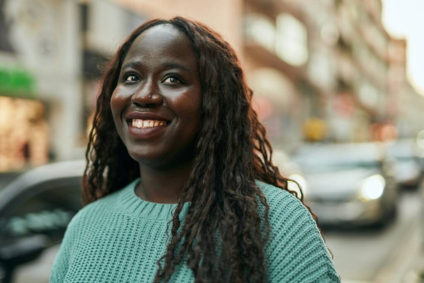 Genç Afrikalı kadın şehirde mutlu gülümsüyor. - Fotoğraf, Görsel