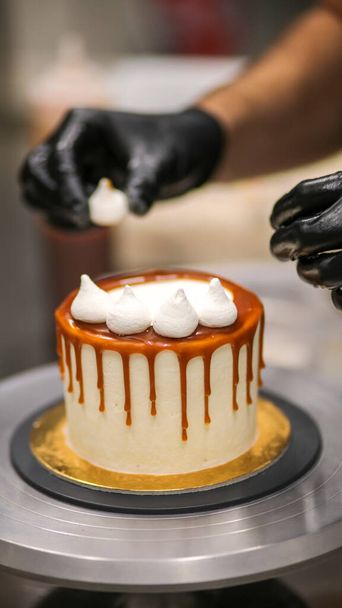 chef-kok versieren van de top van een glazuur boterroom taart - Foto, afbeelding