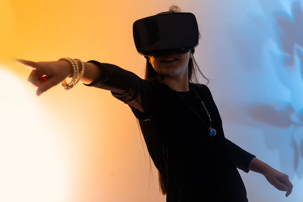 Дівчата-підлітки розважаються, граючи в окуляри VR віртуальної реальності, граючи в ігри, переглядаючи фільми, слухаючи музику, купуючи. Барвисті неонові футуристичні фони, технології цифрового майбутнього
 - Фото, зображення