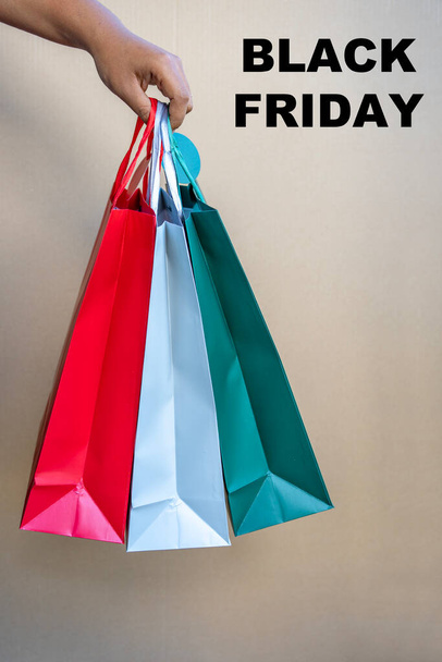 African American woman hand holding Black Friday paper bags isolated on beige background. - Photo, image