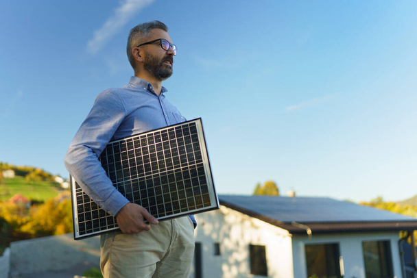 Businessman holding solar panel, standing outdoor at a garden. - Foto, imagen