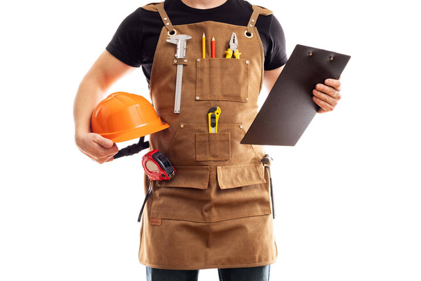Работник подрядчика или плотник в рабочих фартук со шлемом и буфер обмена изолированы на белом фоне - Фото, изображение