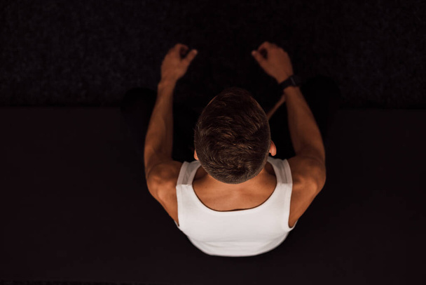 Elleriyle yoga yapan bir adam dizlerini tutar. Üst Manzara. Yüksek kalite fotoğraf - Fotoğraf, Görsel