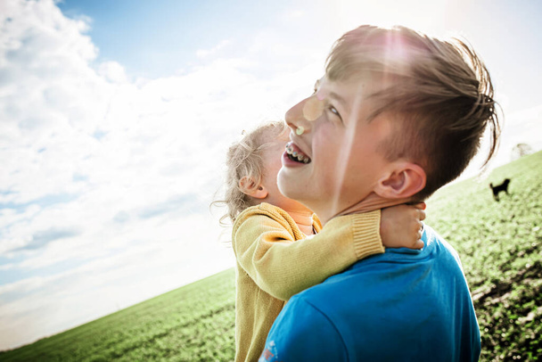 Маленькая девочка обнимает мальчика во время прогулки на природе. Семья на прогулке летом. - Фото, изображение