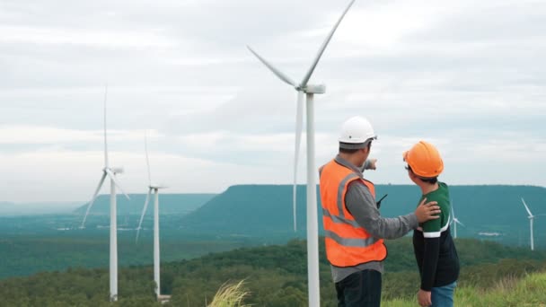 Engineer with his son on a wind farm atop a hill or mountain in the rural. Progressive ideal for the future production of renewable, sustainable energy. Energy generation from wind turbine. - Footage, Video