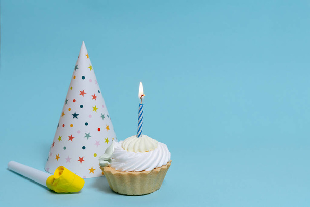 cupcake yksi polttava kynttilä, korkki ja juhlava sarvi sinisellä eristetty tausta tilaa suunnittelu - Valokuva, kuva