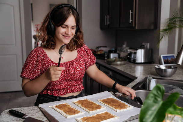 Giovani donne adulte che fanno pasticceria con mele e cottura al forno, sorridendo - Foto, immagini