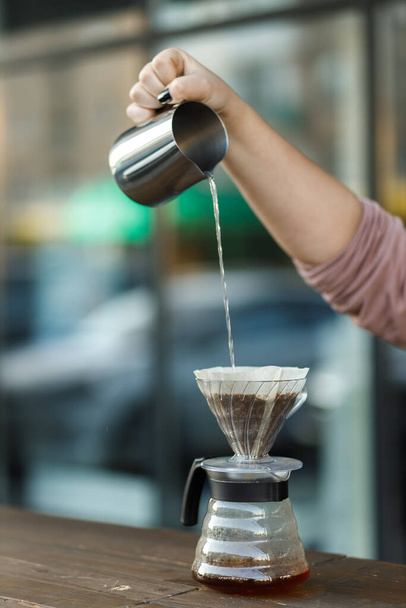 漏斗の中でコーヒーを醸造。漏斗の中のコーヒーを注ぐ。代替方法。暗い背景の美しいテーブル。コーヒーの専門を醸造するプロセス。コーヒーが注いでいる - 写真・画像