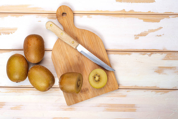 Kiwi sliced and whole fruits on cutting board with knife. On the white table. Copy space - Foto, imagen
