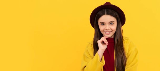smiling kid in hat and coat on yellow background, fall. Child face, horizontal poster, teenager girl isolated portrait, banner with copy space - Fotó, kép