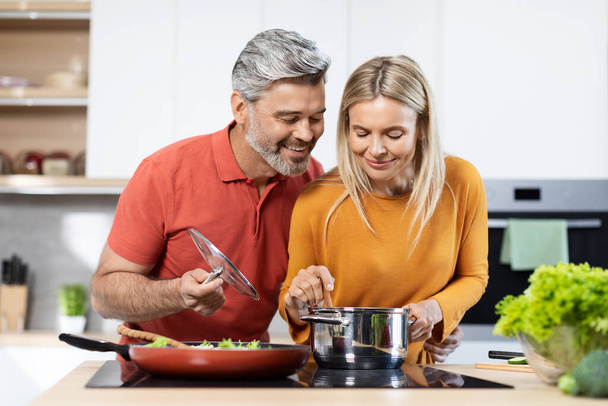 Kaunis keski-ikäinen mies ja nainen ruoanlaitto yhdessä moderni keittiö, myrkyllinen pari tekee terveellistä herkullista illallista kotona. Terveellinen elämäntapa, ruokavalio, ravitsemus käsite - Valokuva, kuva