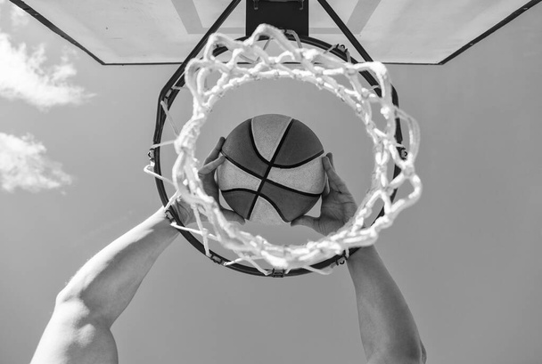 Profispieler. Sporterfolg. Punkteteilung beim Basketballspiel. Die Sicht von oben auf den Ball geht durch den Korb. Mann wirft den Ball in Reifen. Hände und Basketball. Korb für Korb. Slam Dunk in Bewegung. - Foto, Bild