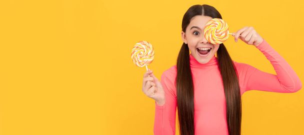 erstaunt teen girl mit lollipop candy auf stick auf gelbem hintergrund, süßer zahn. - Foto, Bild