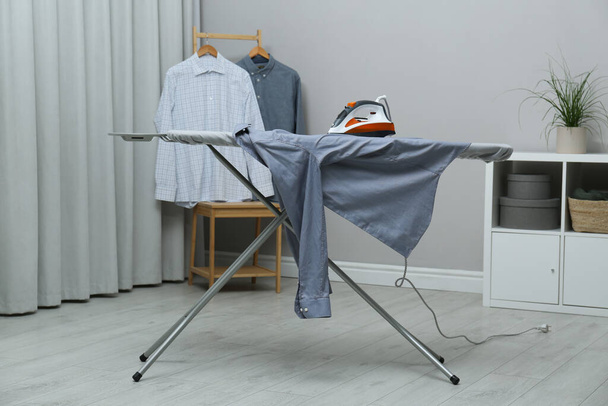 Modern iron and grey clean shirt on board indoors - Φωτογραφία, εικόνα
