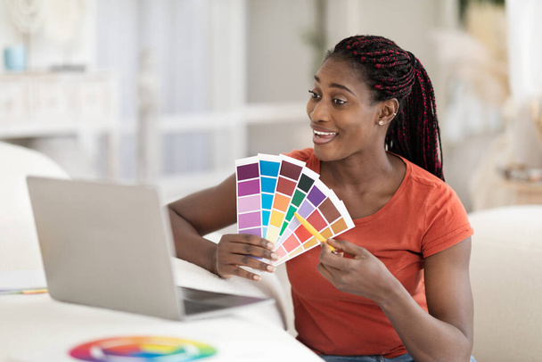 Távoli munka. Fekete női belsőépítész Laptopot használ minták megmutatására ügyfeleknek, mosolygó fiatal afro-amerikai nő bemutatja a színes példákat a telekonferencia alatt, szabad tér - Fotó, kép