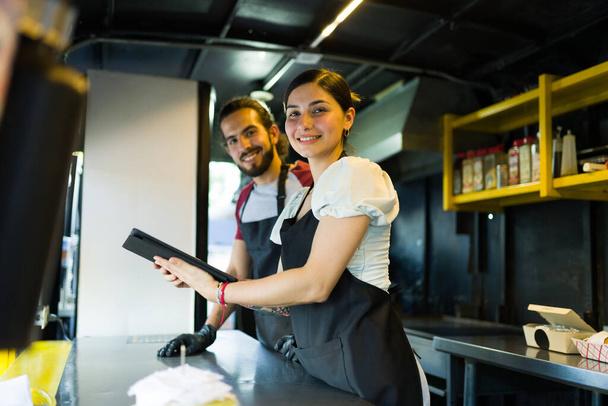 Fornecedor de stall feliz e cozinheiro sorrindo ao verificar as ordens do aplicativo de entrega no caminhão de alimentos - Foto, Imagem