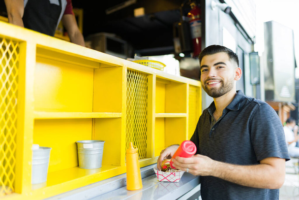 Atrakcyjny młody człowiek i klient gotowi zjeść lunch w fast food trucku - Zdjęcie, obraz