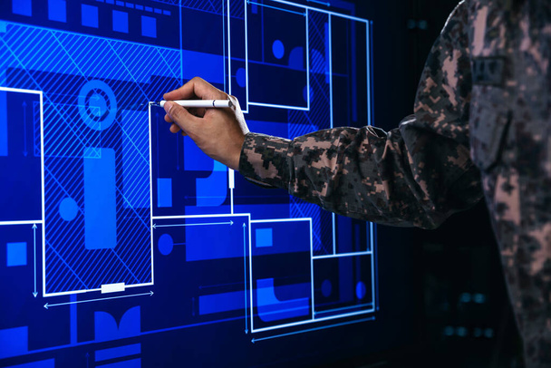 Χέρι του στρατιώτη που δείχνει τη διαχείριση του σχεδίου οικοδόμησης, ανοίγοντας ένα μονοπάτι στην ηλεκτρονική οθόνη. - Φωτογραφία, εικόνα