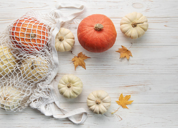 Composizione autunno vista dall'alto con zucche in rete shopping bag su uno sfondo di legno - Foto, immagini