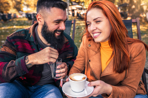 Прекрасная любящая пара, сидящая в кафе, наслаждаясь кофе и беседой
. - Фото, изображение