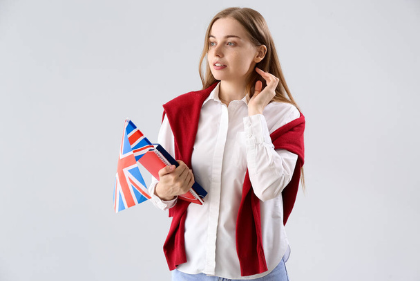 Young woman with UK flag and books on light background - Photo, Image