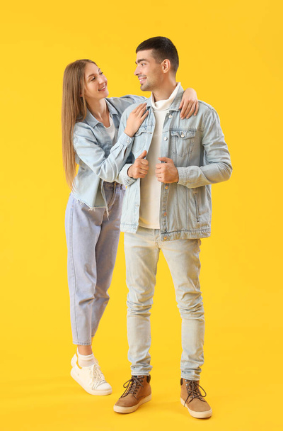 Fashionable young couple in autumn clothes on yellow background - Photo, Image