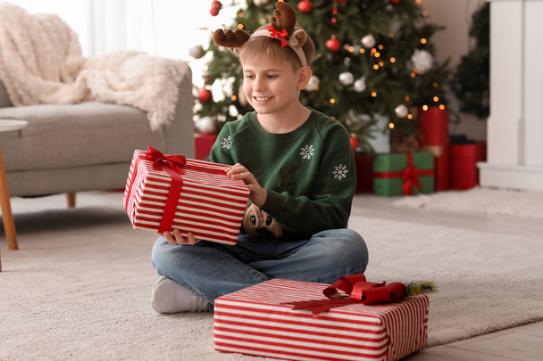Gelukkige kleine kinderen in rendieren hoorns met kerstcadeau thuis - Foto, afbeelding