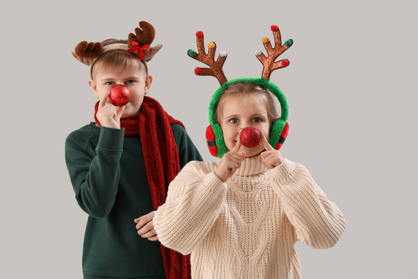 Happy little children in reindeer horns with Christmas balls on light background - Fotoğraf, Görsel