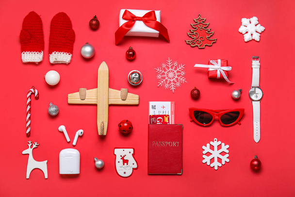 Accesorios de viaje con decoración navideña y regalos sobre fondo rojo - Foto, Imagen