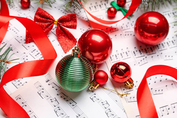 Рождественские шары с бантом и лентой на нотных простынях, крупным планом - Фото, изображение