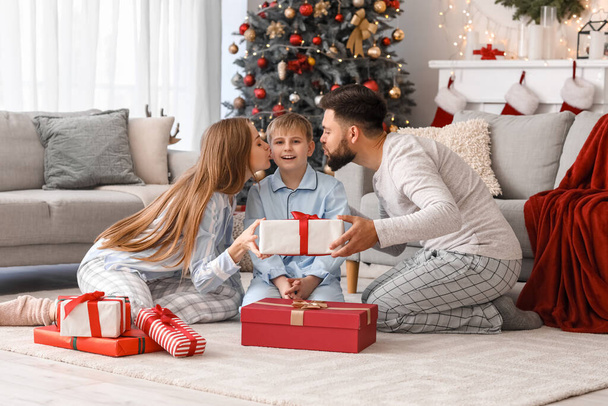 Ευτυχισμένοι γονείς με τον μικρό τους γιο και Χριστουγεννιάτικο δώρο στο σπίτι - Φωτογραφία, εικόνα