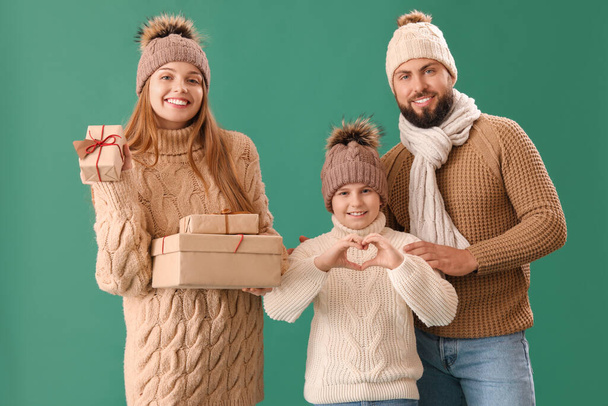 Happy parents with their little son and Christmas presents on green background - Photo, Image
