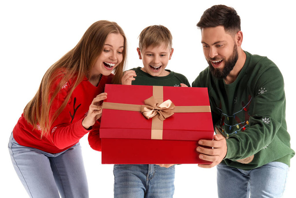 Padres felices con su hijo pequeño abriendo regalo de Navidad sobre fondo blanco - Foto, imagen