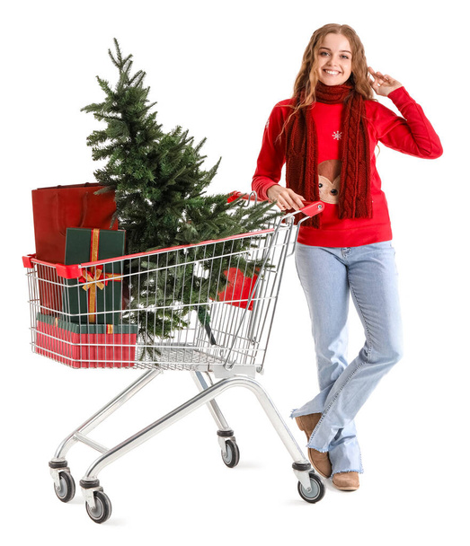 Jovem com carrinho de compras, árvore de Natal e presentes em fundo branco - Foto, Imagem