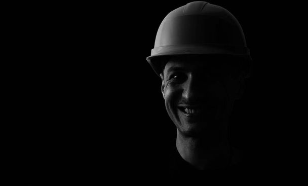 Dirty face of coal miner on a black background. Head of tired mine worker in a hard hat - Foto, Imagem