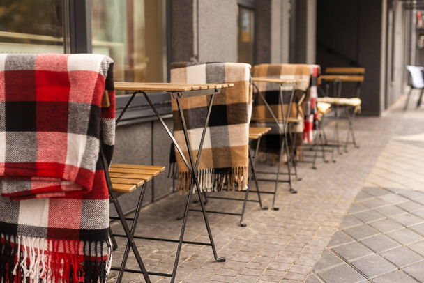 άνετα καθίσματα σε ένα καφέ δρόμο με κουβέρτες. - Φωτογραφία, εικόνα