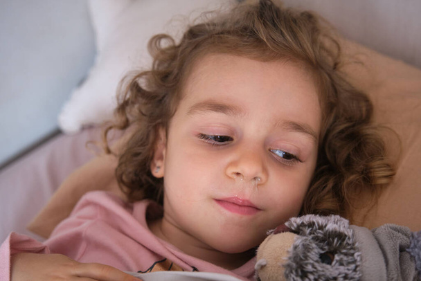 sairas tyttö makaa sängyssä vuotava nenä ja kuume aiheuttama kausiluonteinen virus, makaa peiton peitossa - Valokuva, kuva