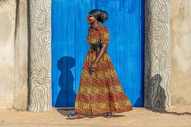 Afrikaanse vrouw met jurk en hoofdtooi loopt in Keta dorp Ghana West-Afrika - Foto, afbeelding