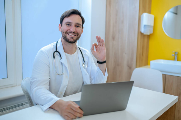Doctors office. Bearded young doctor sitting at the laptop in his office - Photo, Image